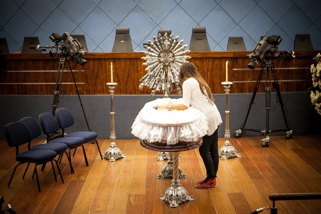 20.abr.2014 - Flávia, viúva de Luciano do Valle, fica ao lado do caixão e presta as últimas homenagens ao marido - Rodrigo Capote/UOL