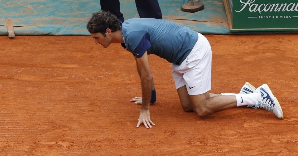 20.abr.2014 - Roger Federer tropeça e cai no saibro durante partida contra Stanislas Wawrinka