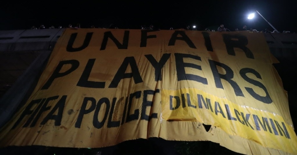 29.abr.2014 - Manifestantes estendem faixa na ponte estaiada sobre a Avenida Sarim Farah Maluf, na zona lesta de São Paulo. Em inglês, bandeira diz que Fifa, polícia, Dilma e Alckmin são "jogadores injustos"