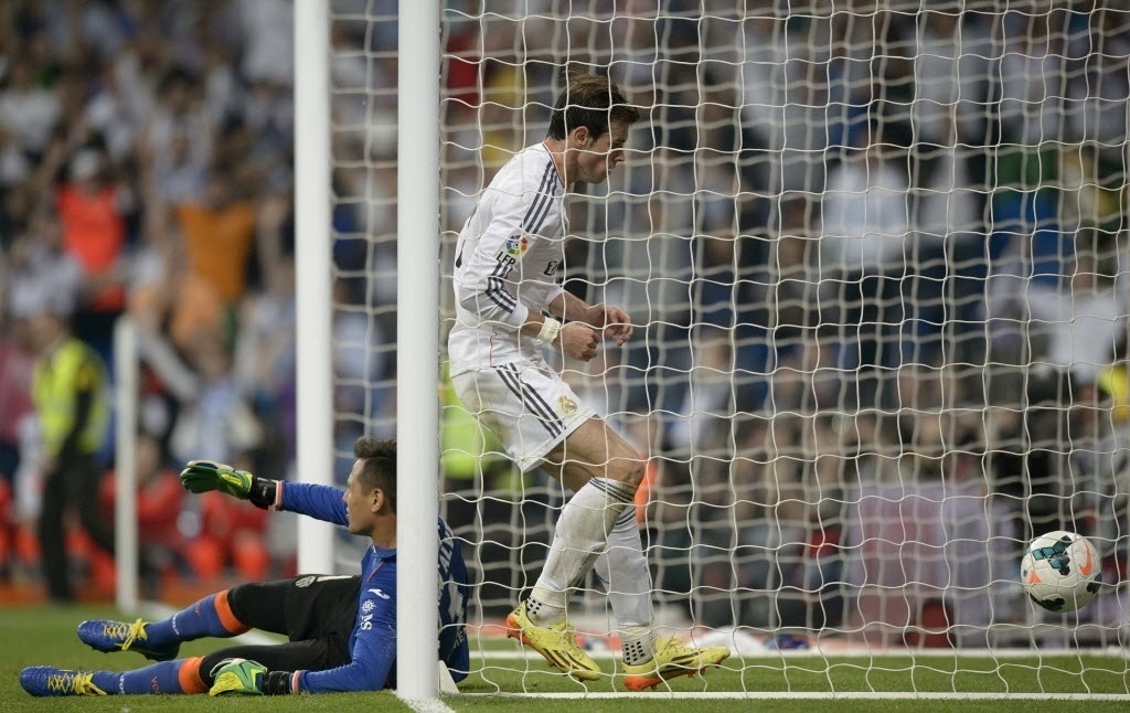 04.mai.2014 - Gareth Bale entra no gol de Diego Alves para pegar a bola após golaço de calcanhar de Cristiano Ronaldo que empatou a partida contra o Valencia - AFP PHOTO/ DANI POZO
