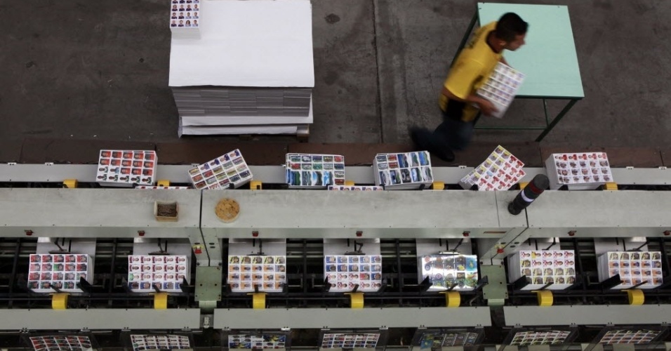 Máquinas e funcionários dividem as etapas de fabricação das figurinhas da Copa do Mundo na fábrica da Panini, em Barueri