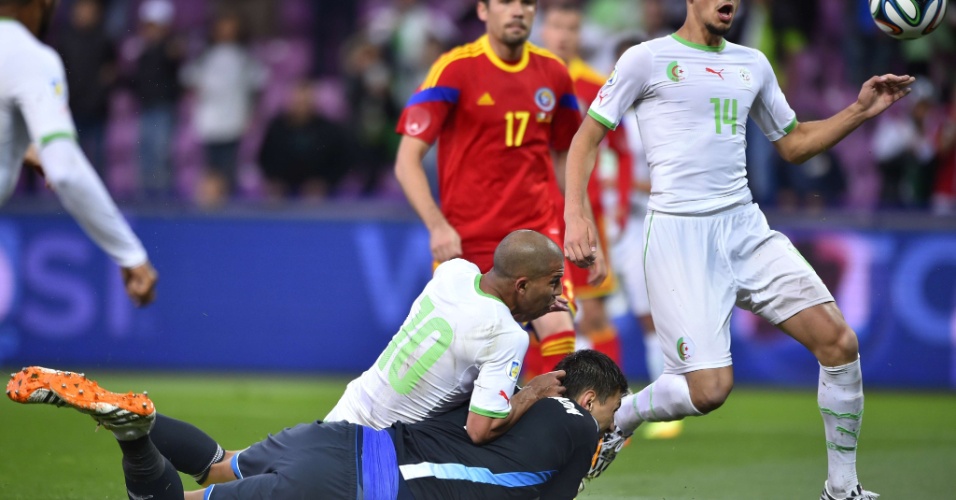 Nabil Bentaleb, da Argélia, divide com goleiro antes da bola cruzar a linha do gol da Romênia em partida amistosa em Genebra