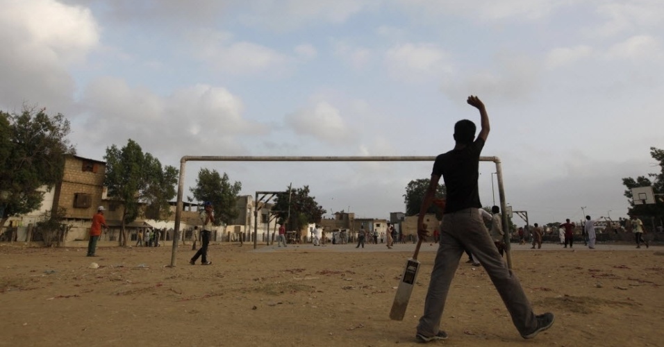 Campo de futebol também é usado para a prática do cricket em uma favela de Carachi, no Paquistão