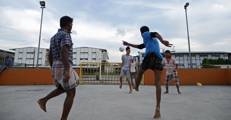 Imigrantes de Bangladesh e Índia se divertem em um campinho de cimento em Singapura