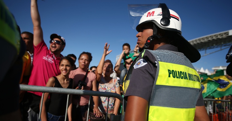 11. jun. 2014 - Policial protege arredores do Itaquerão e torcida faz a festa do lado de fora do estádio