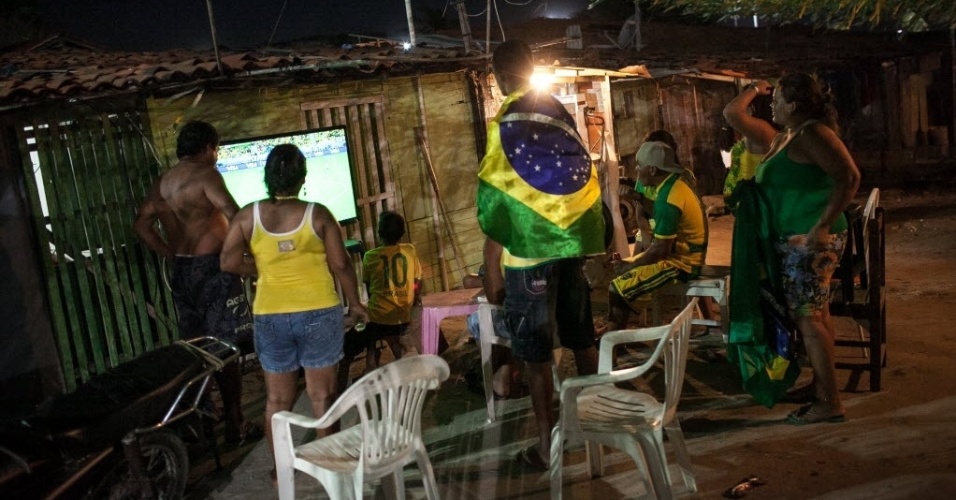 12.jun.2014 - Alguns moradores da Comunidade Raiz da Praia, de Fortaleza, não aguentaram e viram de pé a estreia do Brasil