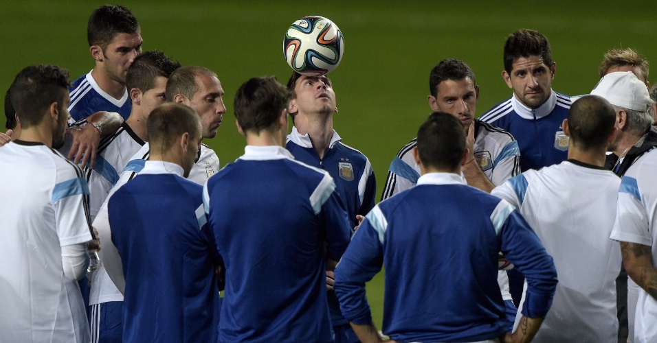 12.jun.2014 - Lionel Messi brinca com a bola enquanto enquanto o técnico Alejandro Sabella conversa com os jogadores da Argentina