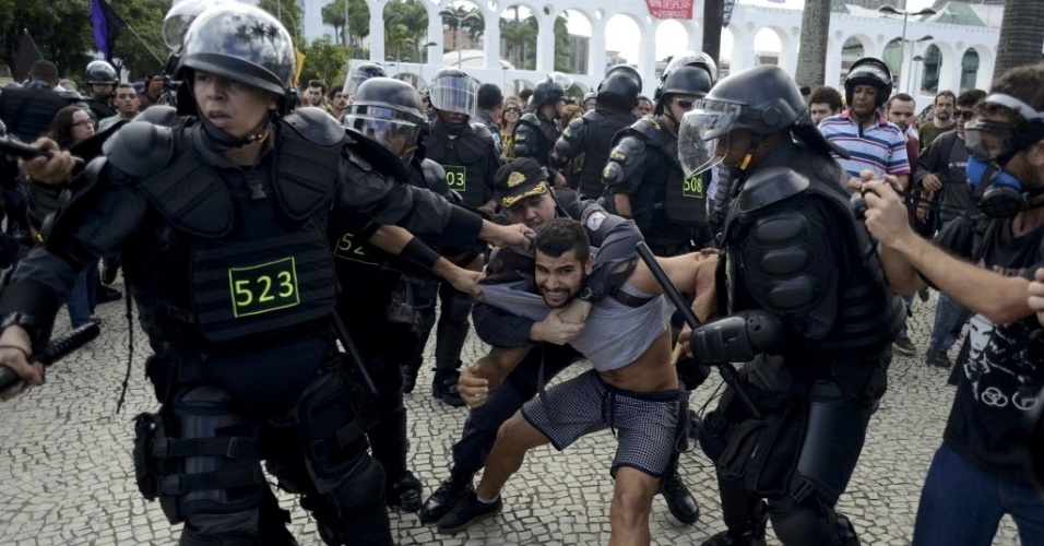 12.jun.2014 - Manifestante é puxado por policiais durante protesto no Rio de Janeiro