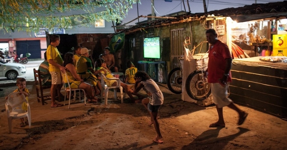 12.jun.2014 - Moradores da Comunidade Raiz da Praia, em Fortaleza, acompanham jogo de estreia do Brasil