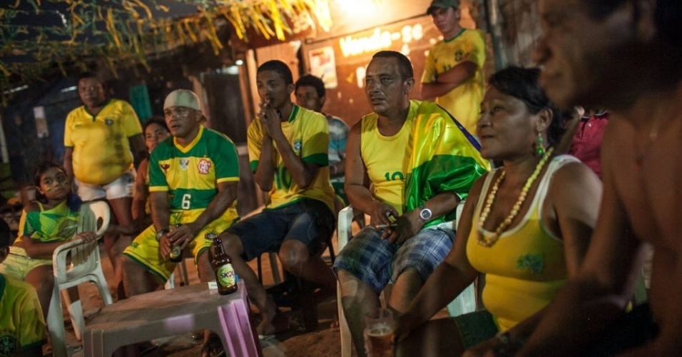 12.jun.2014 - Moradores da Comunidade Raiz da Praia, em Fortaleza, ficam atentos acompanhando a estreia da seleção brasileira