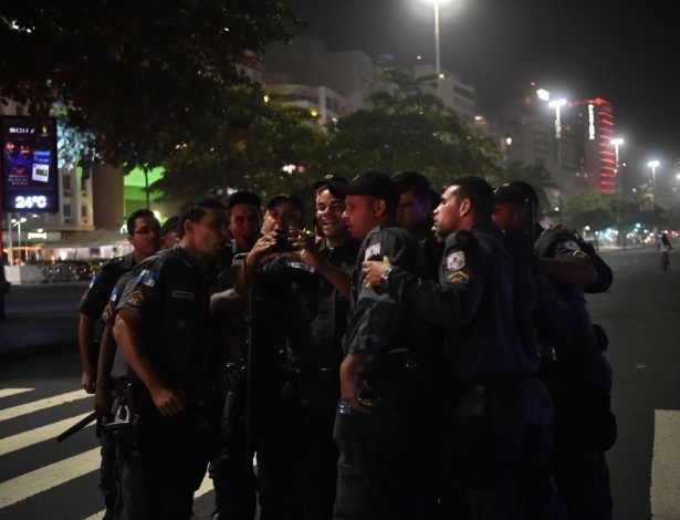 12.jun.2014 - Policiais que faziam a segurança da Fan Fest em Copacabana, no Rio de Janeiro, juntam-se para assistir ao replay do segundo gol do Brasil contra a Croácia