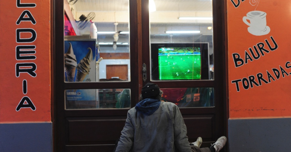 Morador do Chuí curte a estreia da seleção no meio da rua, sozinho, assistindo à partida contra a Croácia em uma vitrine de loja