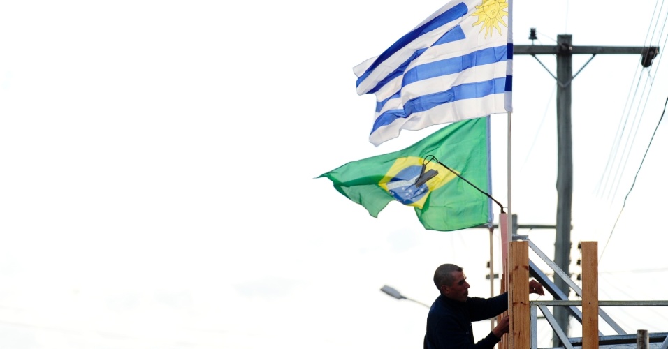Morador do Chuí se prepara para a estreia da seleção na Copa, fixando as bandeiras do Brasil e do Uruguai