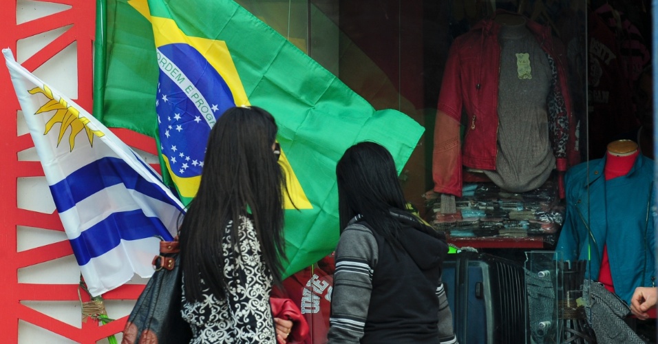 Mulheres passam por comércio na fronteira entre Brasil e Uruguai antes da estreia da seleção na Copa do Mundo