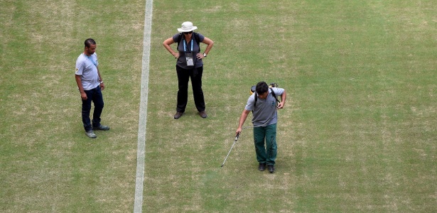 Funcionário usa spray para disfarçar falhas no gramado da Arena Amazônia