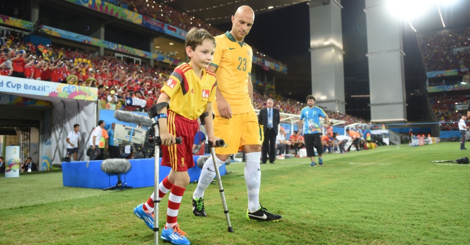 13.jun.2014 - Australiano Mark Bresciano entra no gramado da Arena Pantanal acompanhado de uma criança com deficiência física