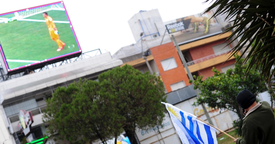 14.jun.2014 - Torcedor com bandeira uruguaia acompanha jogo contra Costa Rica em telão nas ruas de Rivera, fronteira com o Brasil no Rio Grande do Sul