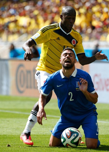 Ibarbo, da Colômbia, entra forte atrás da bola com Giannis Maniatis, da Grécia. Pela cara do grego, doeu um bocado