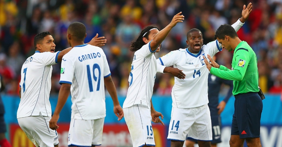 Jogadores de Honduras reclamam com Sandro Meira Ricci após o árbitro brasileiro validar gol da França em que a bola passou por pouco da linha