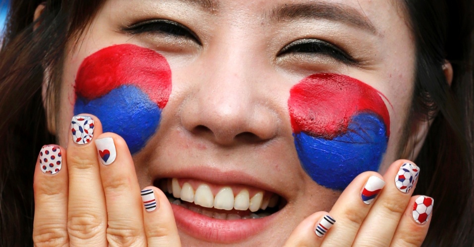 17.jun.2014 - Torcedora coreana pinta o rosto com as cores do país para a partida contra a Rússia, em Cuiabá