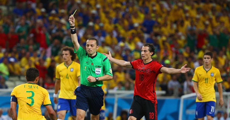 17.jun.2014 - Árbitro Cuneyt Cakir mostra o cartão amarelo para Thiago Silva após o zagueiro cometer falta na entrada da área
