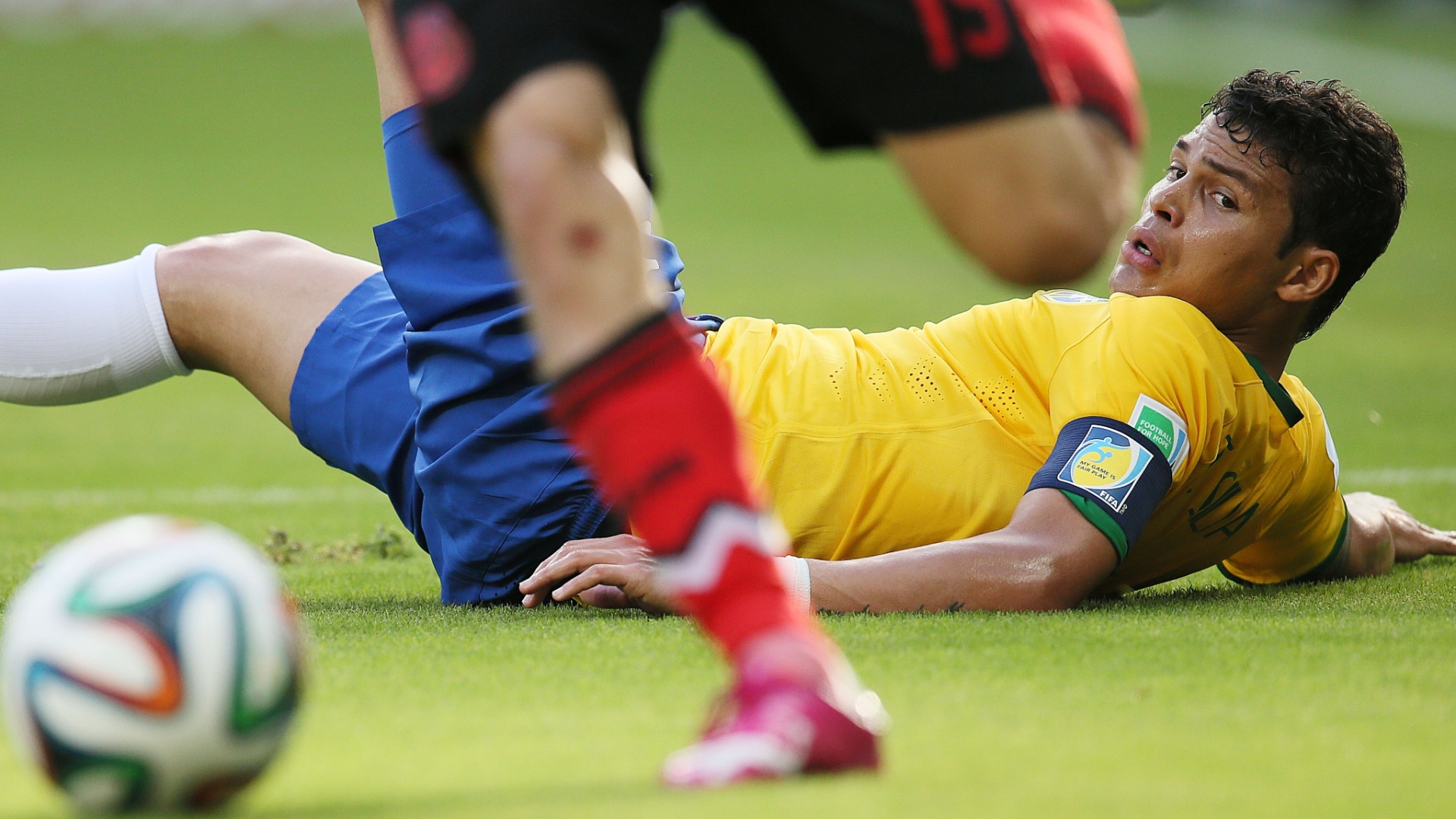17.jun.2014 - Caído no gramado, Thiago Silva observa o mexicano Oribe Peralta sair jogando com a bola dominada no Castelão