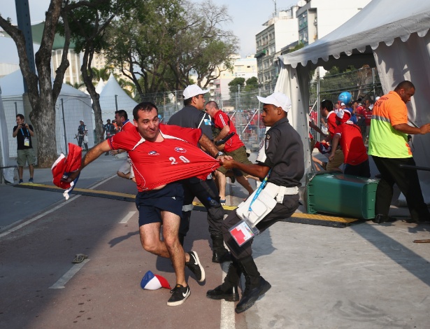 Policial tenta conter torcedor chileno durante invasão ao centro de imprensa do Maracanã
