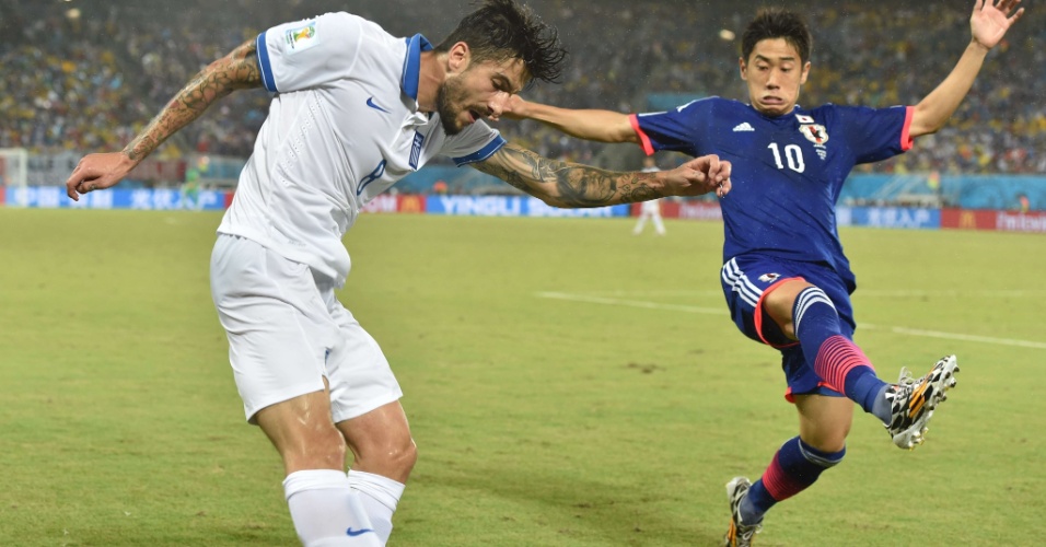 Armador da seleção japonesa, Shinji Kagawa ajuda na marcação em tentativa de passe do grego Panagiotis Kone