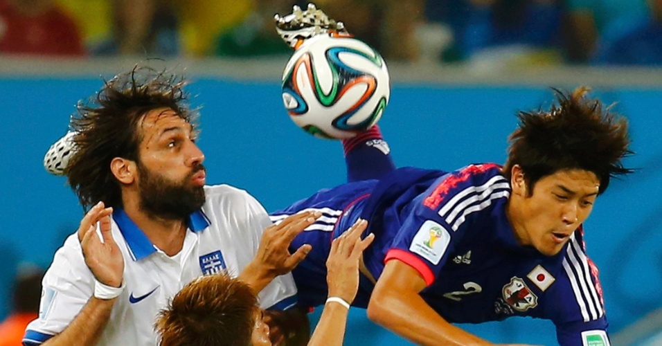 Georgios Samaras, da Grécia, observa a bola enquanto o japonês Atsuto Uchida começa a se proteger antes de cair no gramado