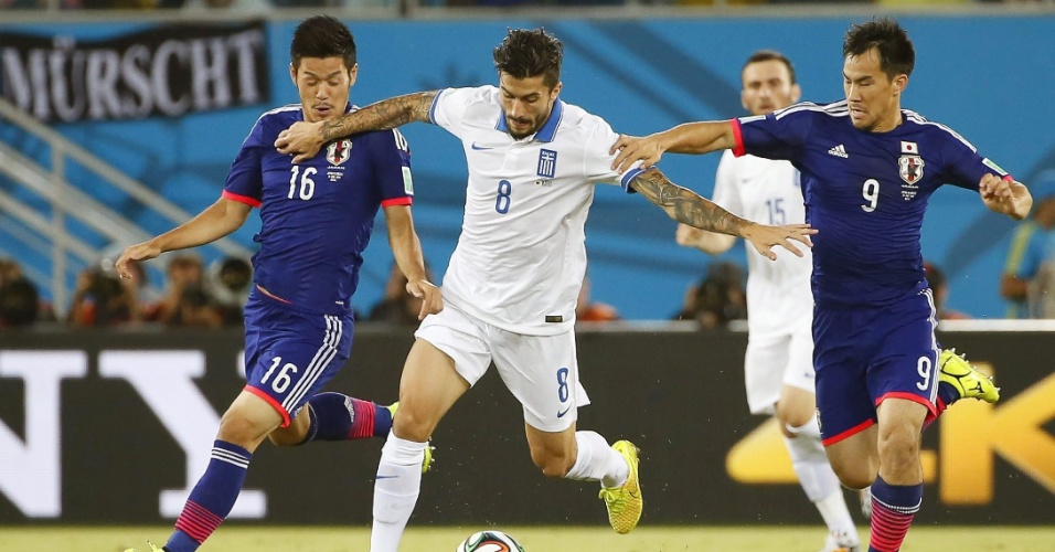 Grego Panagiotis Kone protege a bola entre dois jogadores japoneses