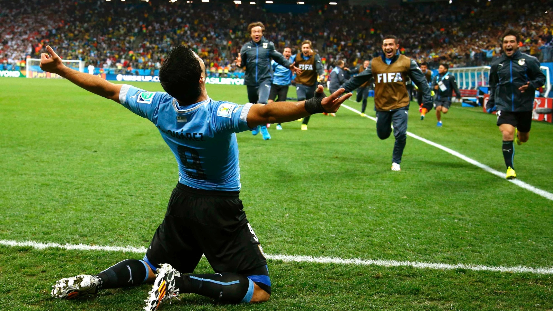 19.jun.2014 - Luis Suárez abre os braços e aguarda companheiros uruguaios para comemorar o segundo gol contra a Inglaterra