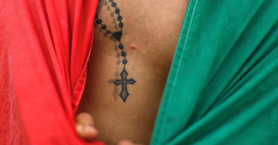 Mexicano envolto em bandeira do México exibe terço tatuado no corpo