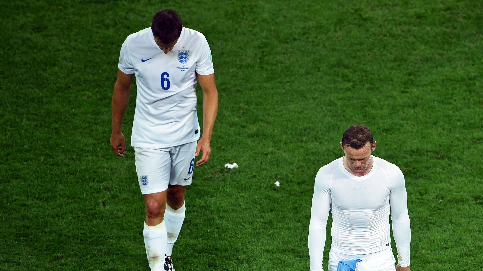 19.jun.2014 - Phil Jagielka (esquerda) e Wayne Rooney deixam o gramados cabisbaixos após a derrota da Inglaterra no Itaquerão