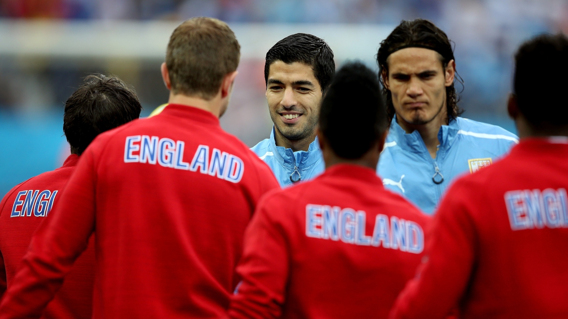 19.jun.2014 - Titular do Uruguai, Luis Suárez sorri ao cumprimentar jogadores ingleses antes do jogo no Itaquerão