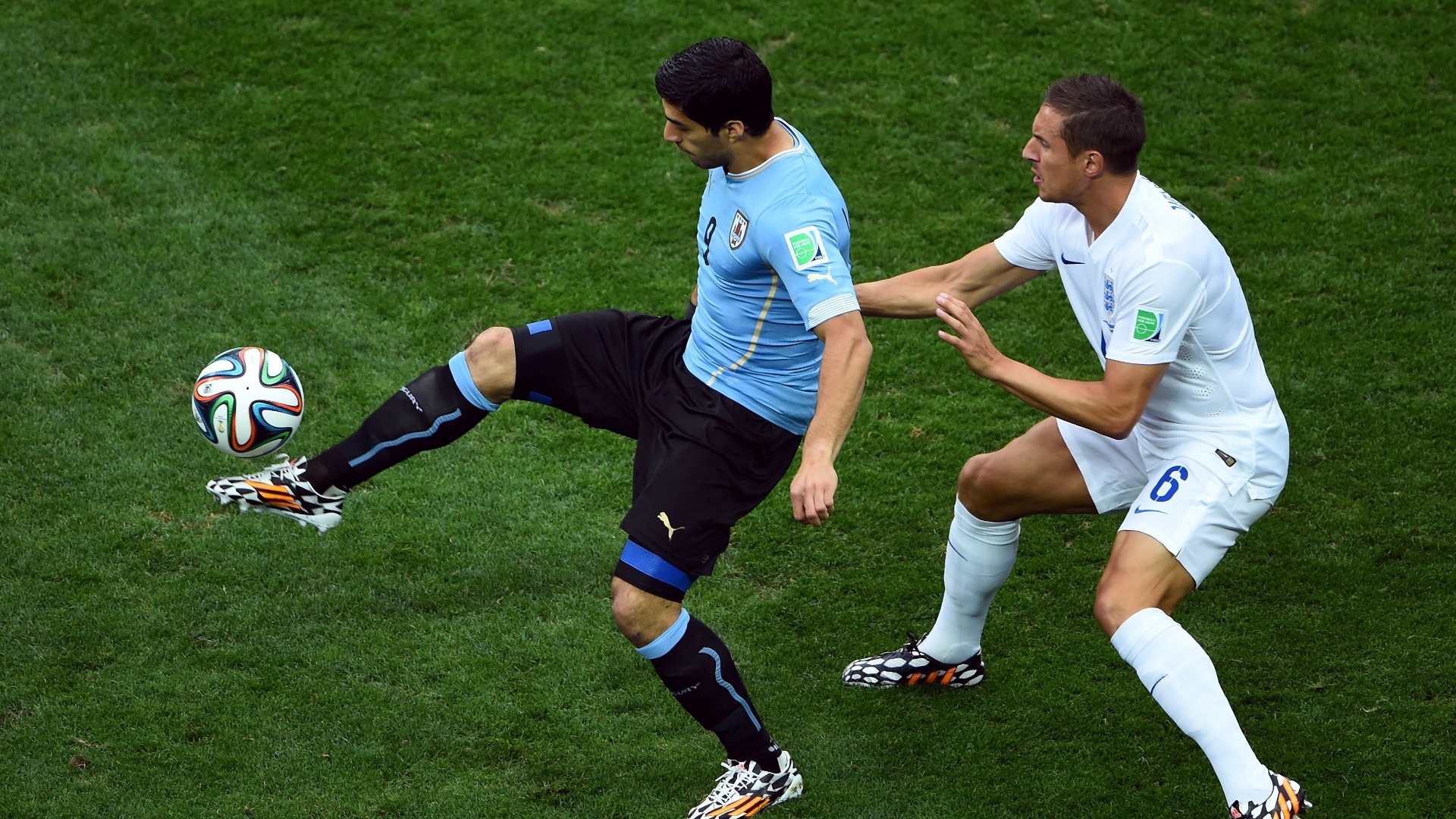 19.jun.2014 - Uruguaio Luis Suárez domina a bola marcado de perto pelo inglês Jagielka, no início da partida no Itaquerão