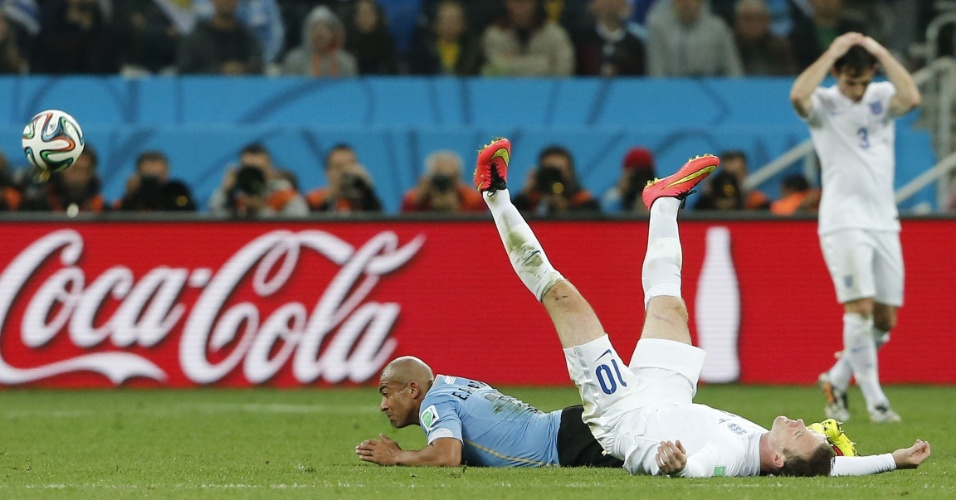 19.jun.2014 - Wayne Rooney fica de pernas para o ar após dividir a bola com o uruguaio Arévalo no Itaquerão