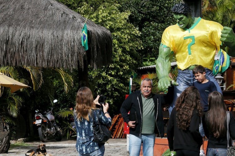 Fãs se aproximam da estátua do Hulk em um restaurante próximo à Granja Comary