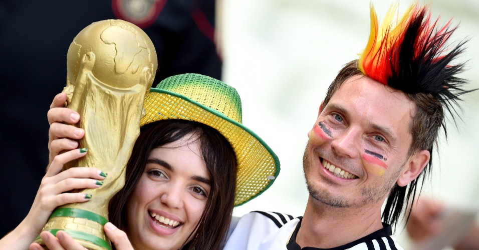 21.jun.2014 - Brasileira e alemão seguram réplica da taça da Copa antes do jogo entre Alemanha e Gana, no Castelão