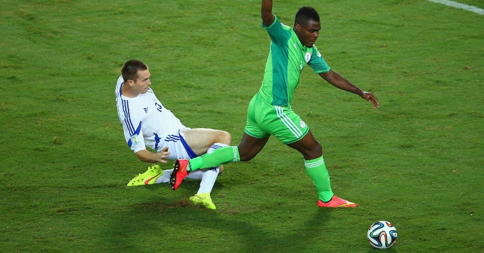 Toni Sunjic, da Bósnia, fica no chão enquanto Emmanuel Emenike, da Nigéria, segue com a bola