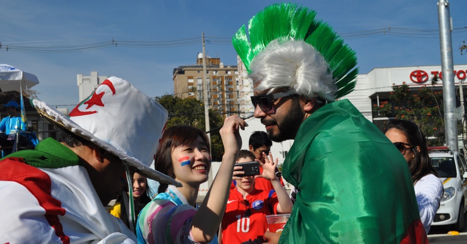 22.jun.2014 - Sul-coreana pinta o rosto de argelino antes do duelo entre as duas seleções