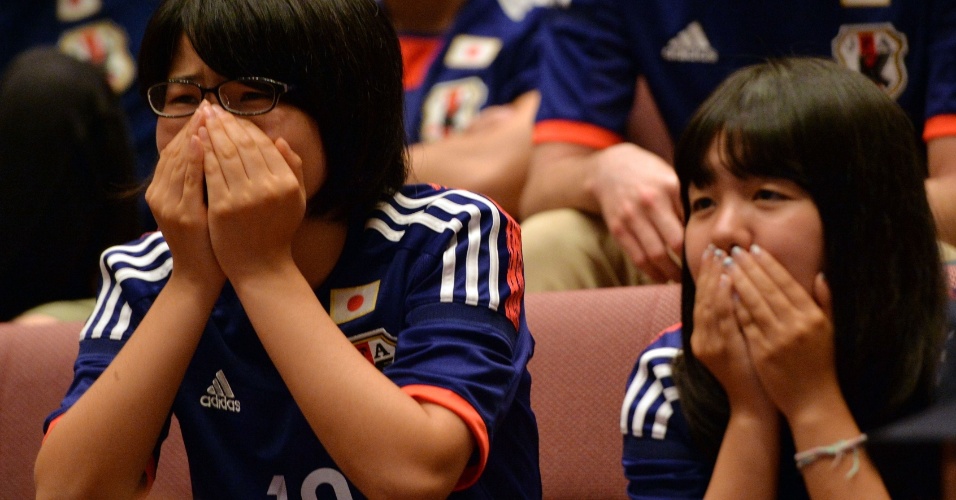 24.jun.2014 - Em Tóquio, torcedoras japonesas ficar perto de irem às lágrimas após eliminação precoce da seleção na Copa