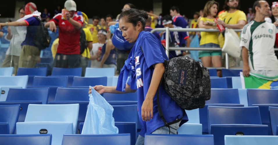 24.jun.2014 - Mesmo triste com a derrota do Japão, torcedora recolhe o lixo na arquibancada da Arena Pantanal