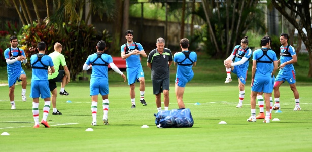 Carlos Queiroz caminha pelo gramado do Barradão enquanto os jogadores do Irã fazem treinos físicos