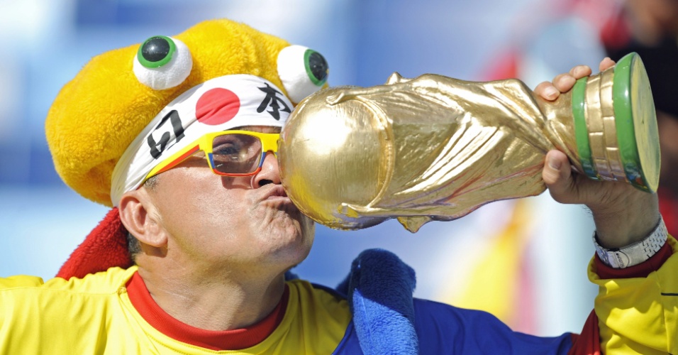 Torcedor beija réplica da taça da Copa do Mundo na Arena Pantanal, antes do jogo entre Japão e Colômbia