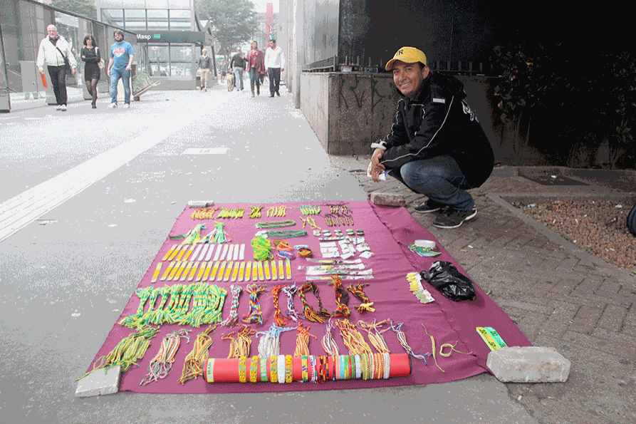 Colombiano Person Domingues sorri em frente a suas peças de artesanato expostas na calçada em frente à Fiesp