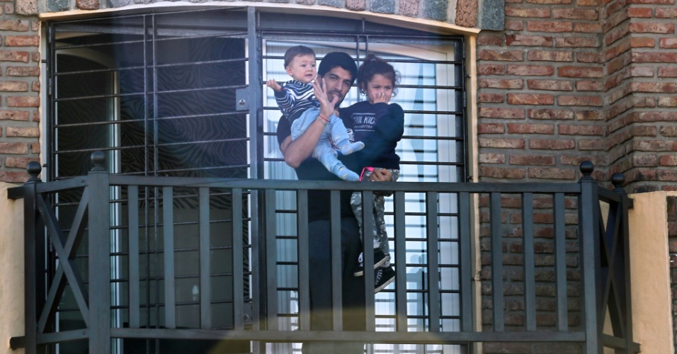 Fora da Copa, Luis Suárez acena para os fãs da janela da casa onde o jogador está hospedado, no Uruguai. O jogador apareceu junto aos filhos Benjamin e Delfina