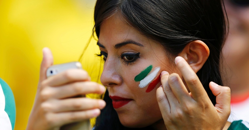 Torcedora mexicana usa celular como espelho para pintar o rosto com as cores do país
