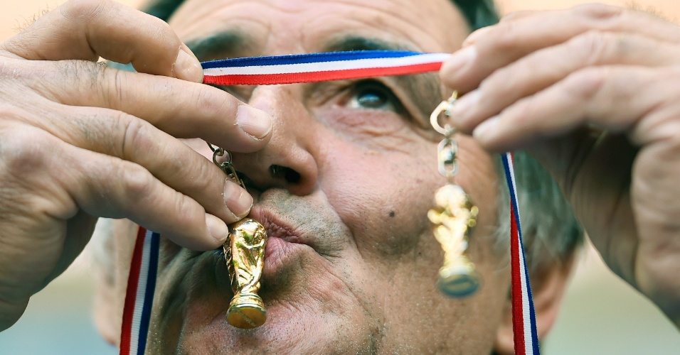 30.jun.2014 - Torcedor francês beija chaveiros com miniaturas da taça da Copa do Mundo durante o jogo contra a Nigéria
