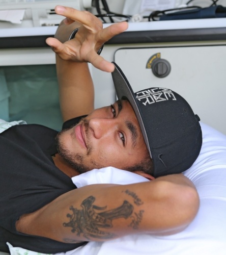 Já deitado na maca em que deixou a Granja Comary, Neymar volta a sorrir após a lesão na vértebra