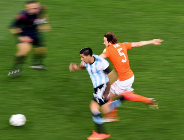 Enzo Perez tenta escapar da marcação de Blind na semifinal entre Argentina e Holanda